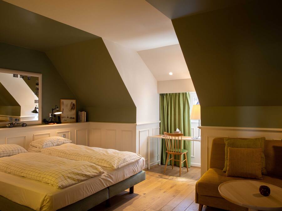 A bedroom with a bed, a desk, and a chair.