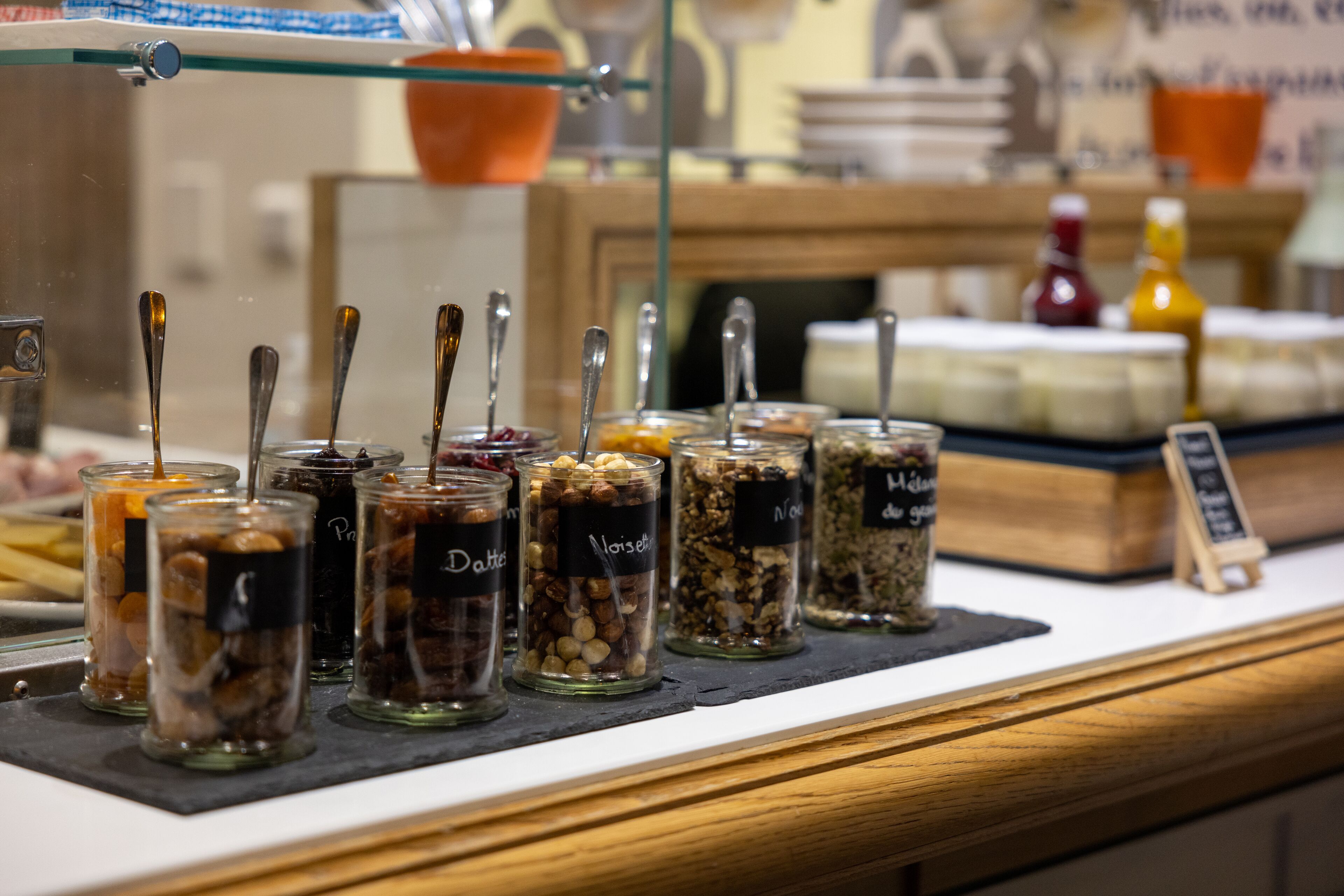 Un banco buffet con diversi cibi esposti in vasetti con le etichette.