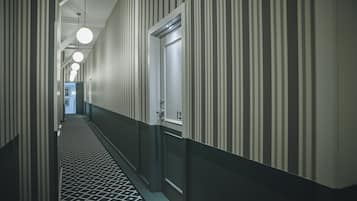 A hotel hallway with striped walls, a patterned floor, and doors numbered 12 and 13.