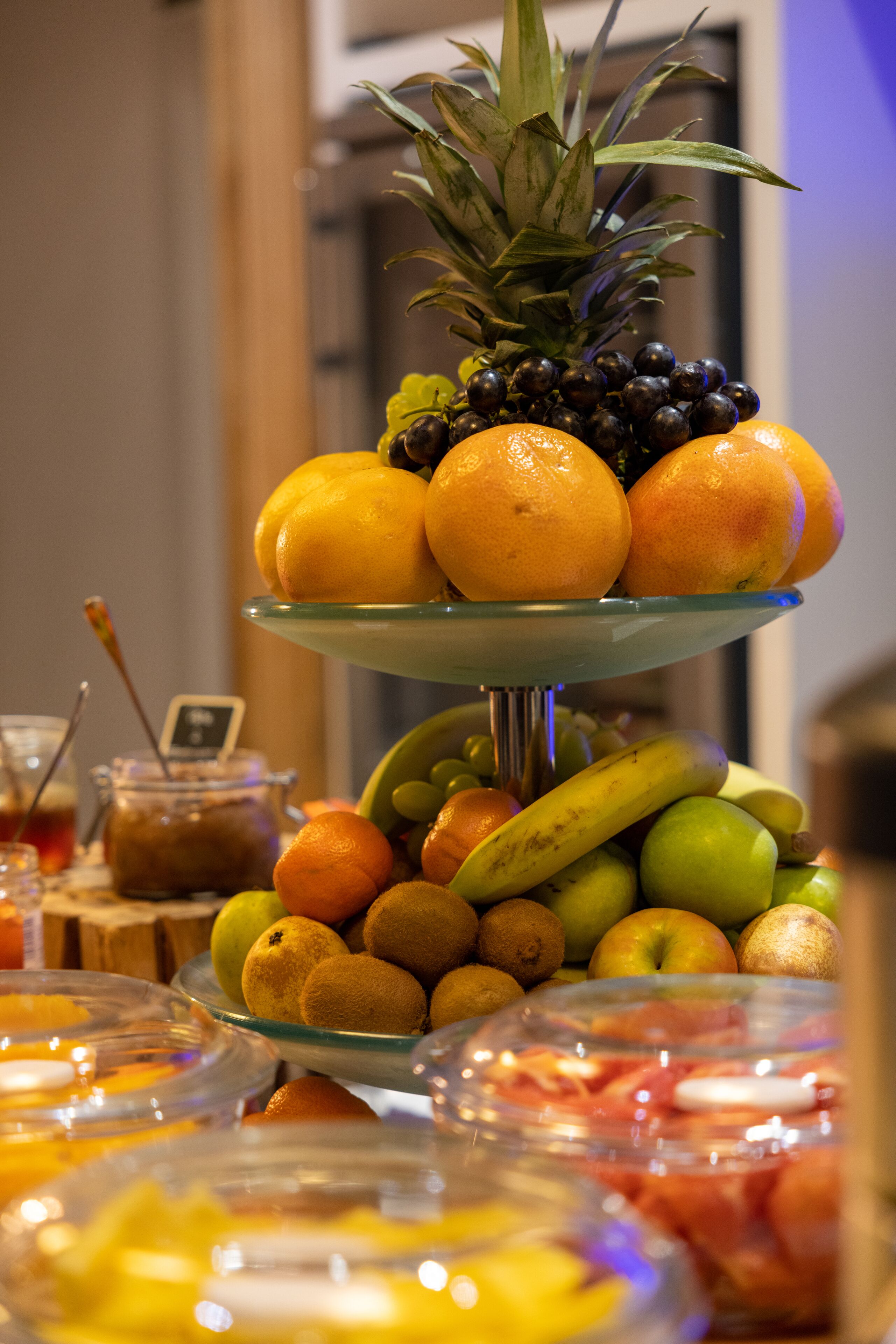 En flot frugtstander med appelsiner, bananer, æbler og en ananas.