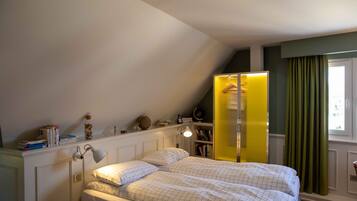A bedroom with a bed, bedside table, lamp, and a bookshelf.
