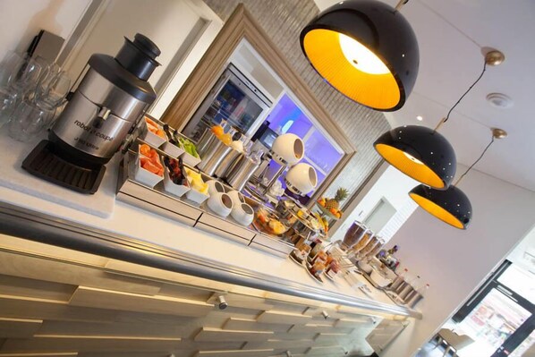 A modern hotel lobby with a coffee machine, seating area, and a large screen displaying content.