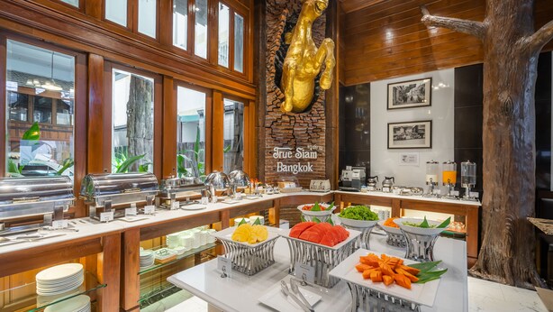 Disposição de buffet com diversos alimentos e um letreiro indicando 'True Siam Bangkok'.