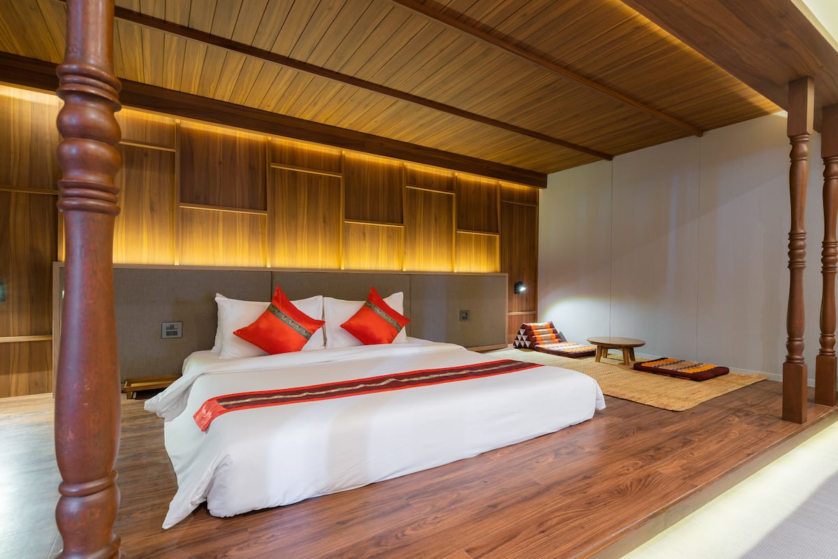 Un dormitorio amplio con una cama grande, techo de madera y suelo de madera.