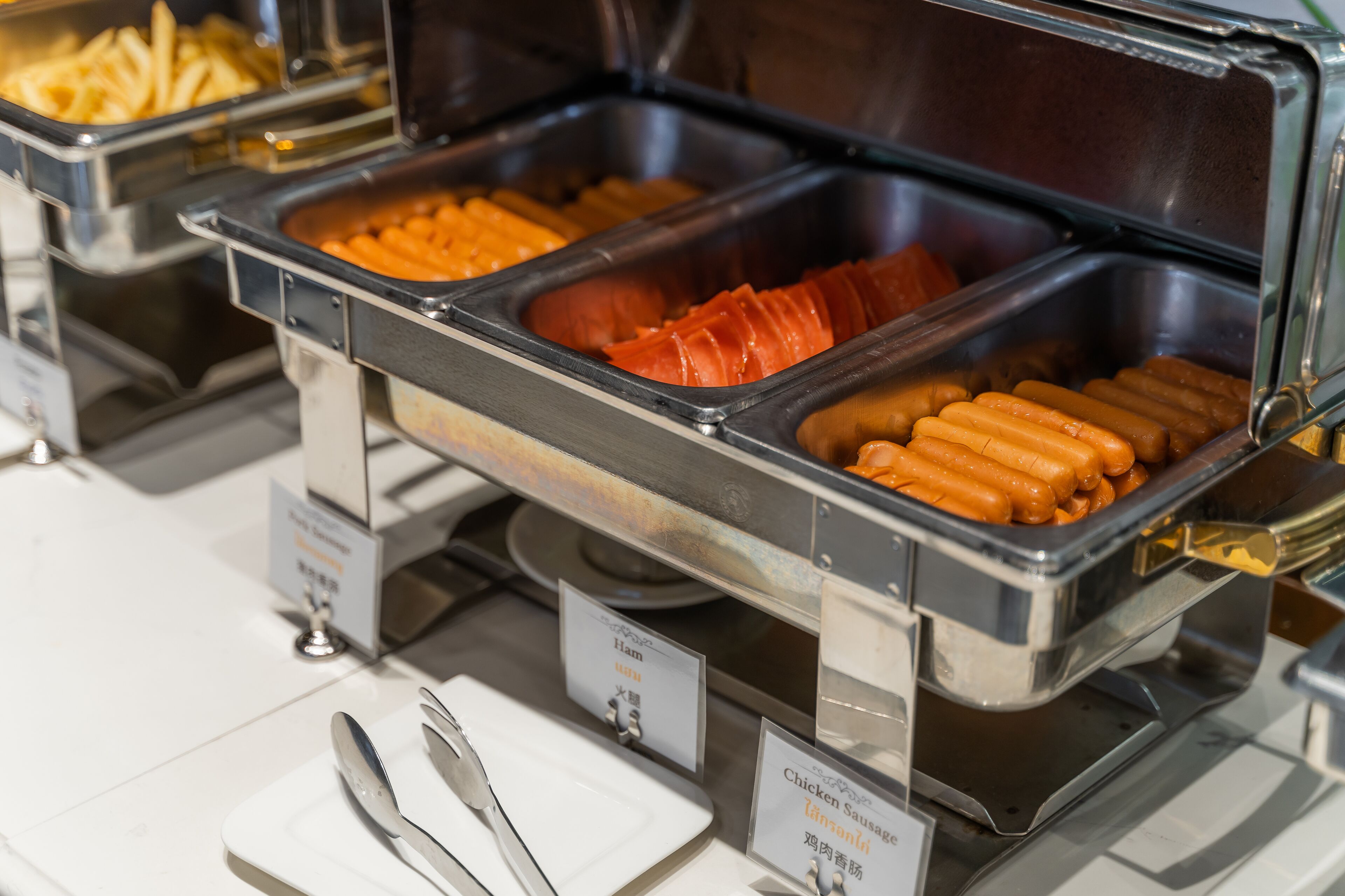 Un buffet avec des présentoirs clairement identifiés pour le jambon, les saucisses de poulet et autres produits.