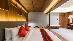 Quarto de hotel com uma cama grande, paredes de painel de madeira, uma pequena mesa redonda e um banco.