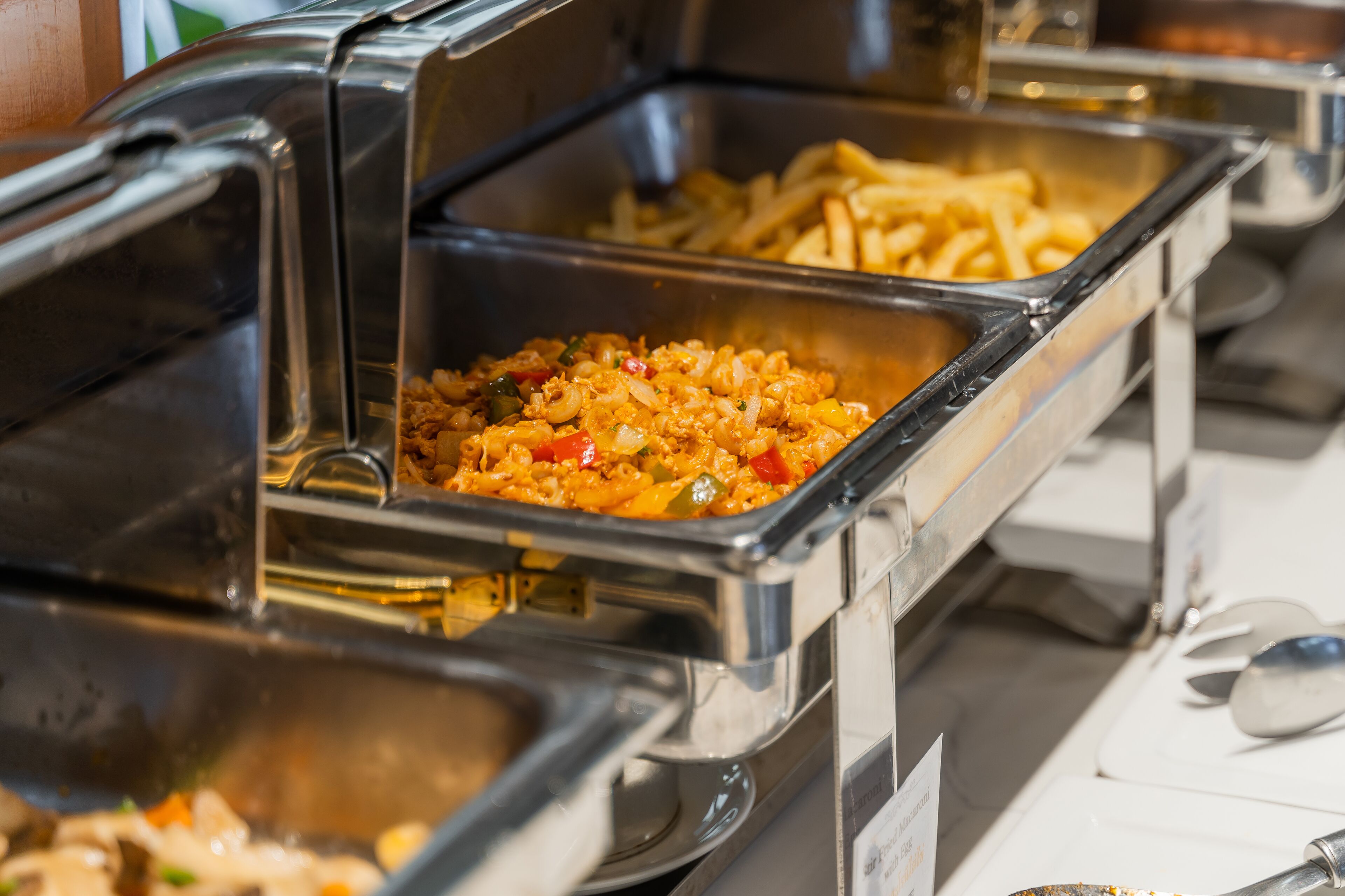 Ein Buffet mit verschiedenen Speisen, darunter Pasta, Reis und Pommes.