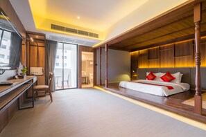 Habitación de hotel con cama, escritorio, silla y vistas al exterior.