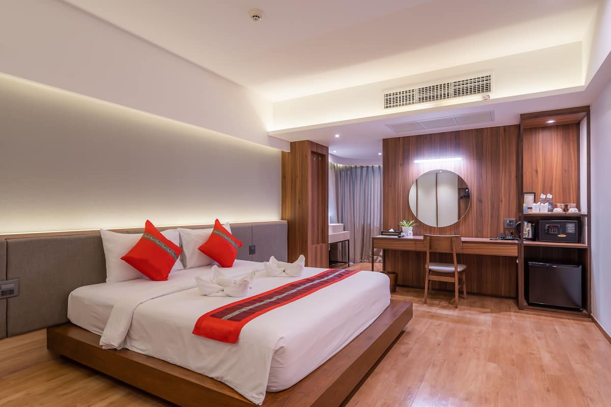 Habitación de hotel con una cama, un escritorio, una silla, un microondas y un refrigerador.