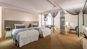 A hotel room with two beds, a desk, a chair, and a television.