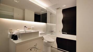 A modern bathroom with a white vanity, a toilet, a bathtub, and a large mirror.