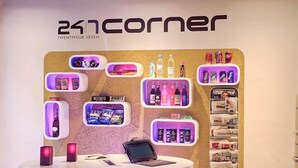 Un kiosco abierto las 24 horas en una esquina, con varios bocadillos, bebidas y una computadora portátil sobre el mostrador.