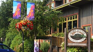 A wooden building with a sign reading "Howe Sound Inn & Brewing Company" and a flower basket.