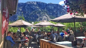 Un área de comedor al aire libre con mesas y sillas, rodeada de montañas.
