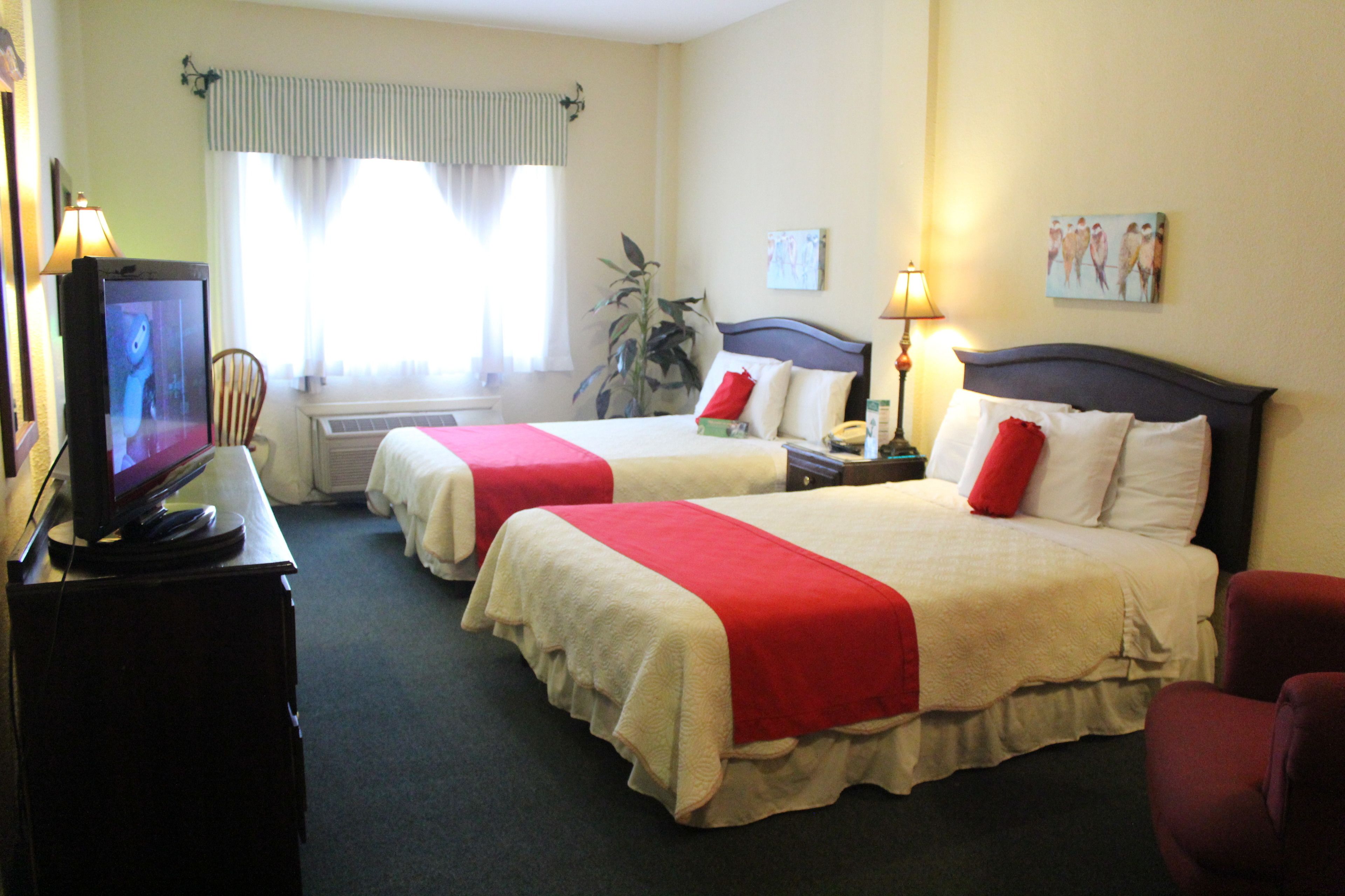 Une chambre d’hôtel avec deux lits, une télévision, un bureau et une chaise.