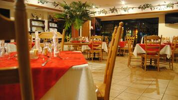 A restaurant with multiple tables set for dining, each with a red tablecloth and white napkins.