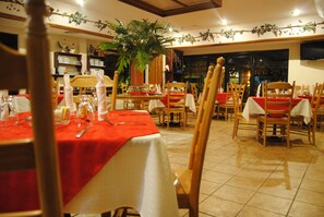 A restaurant with multiple tables set for dining, each with a red tablecloth and white napkins. - Aparthotel La Cordillera (San Pedro Sula)