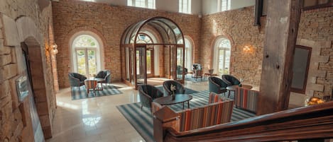 A spacious lobby with stone walls, multiple seating areas, and a staircase leading to upper floors.