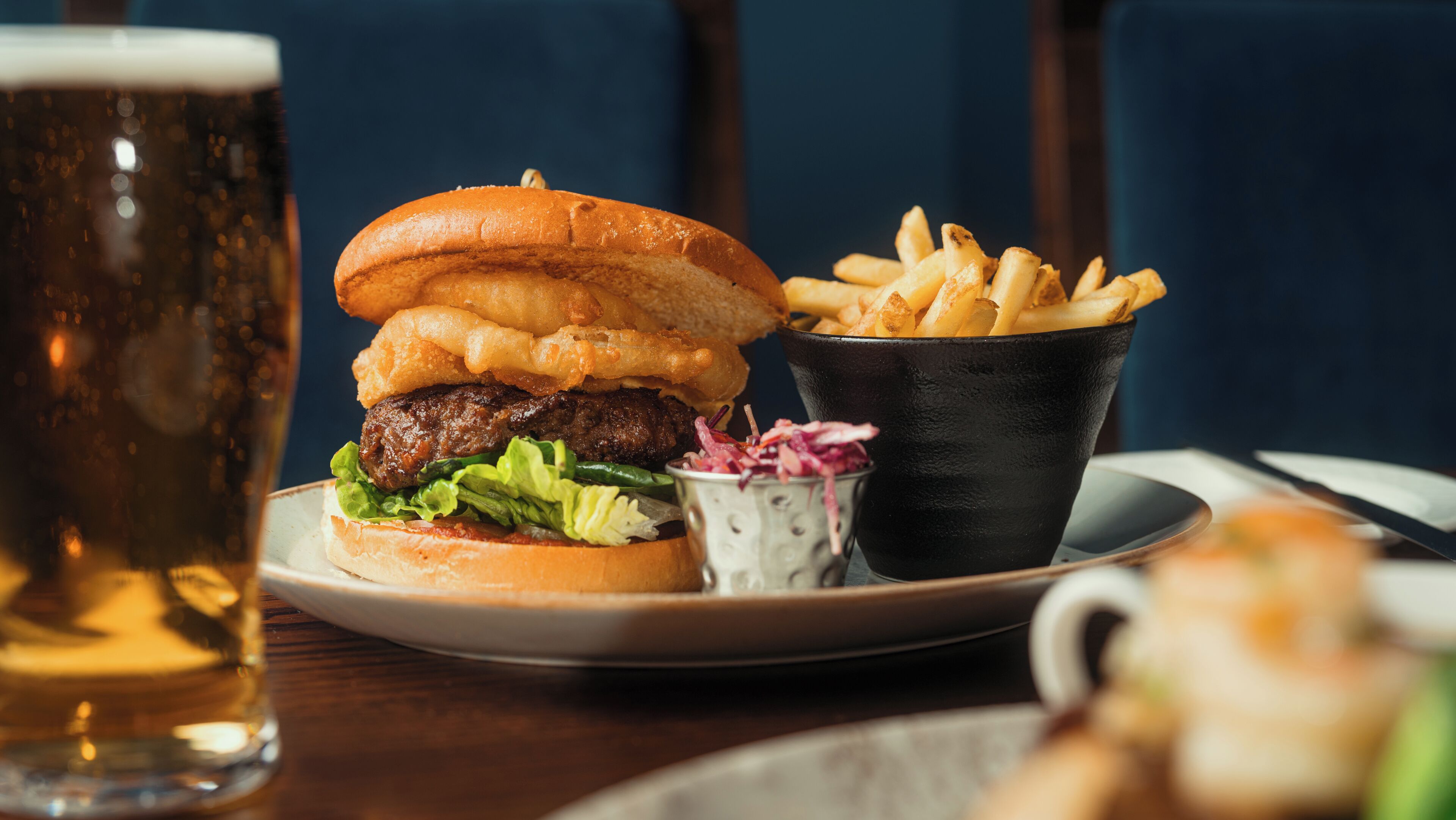 A meal consisting of a burger, fries, and a beer.
