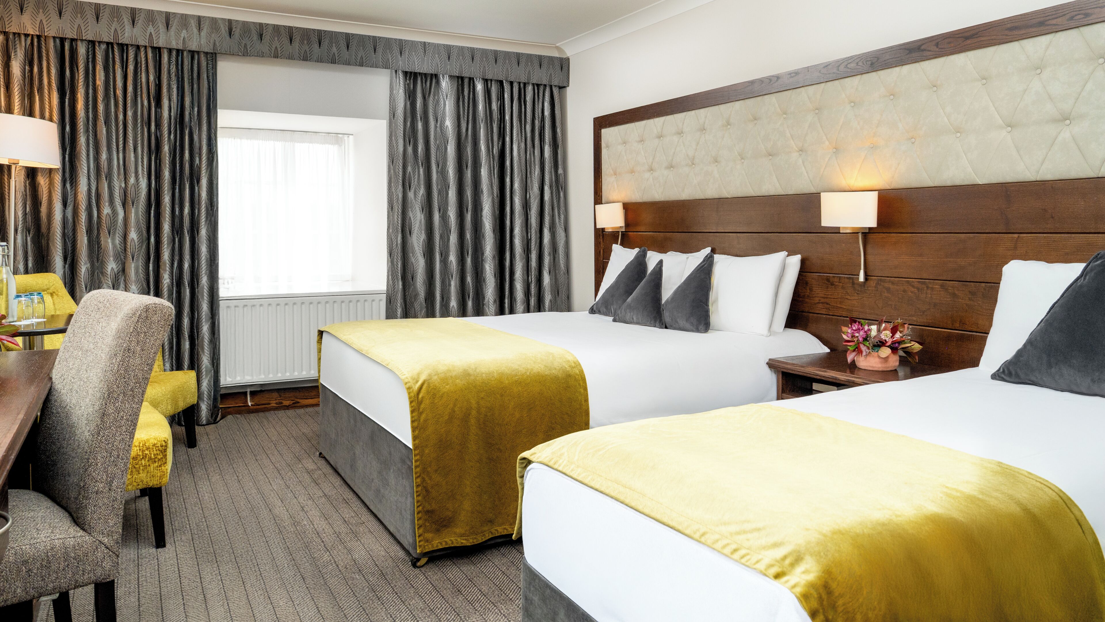 A hotel room with two beds, a desk, and a chair.
