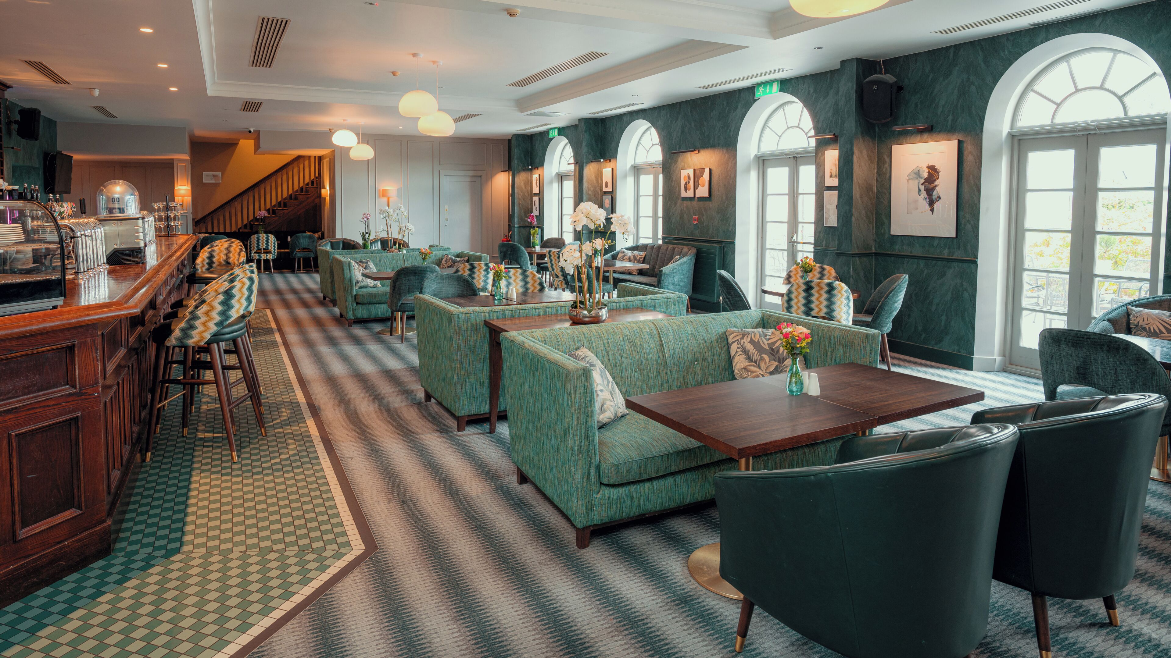 Un vestíbulo de hotel con área de bar, disposición de asientos y obras de arte en las paredes.