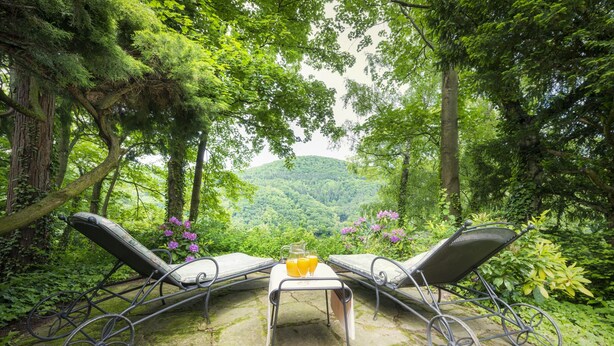 A stone patio with two metal-framed lounge chairs facing a lush green landscape. - Parkhotel Atlantic Heidelberg (Heidelberg)