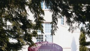 A hotel entrance with a sign reading "Schloss Hotel Atlantic." - Parkhotel Atlantic Heidelberg (Heidelberg)