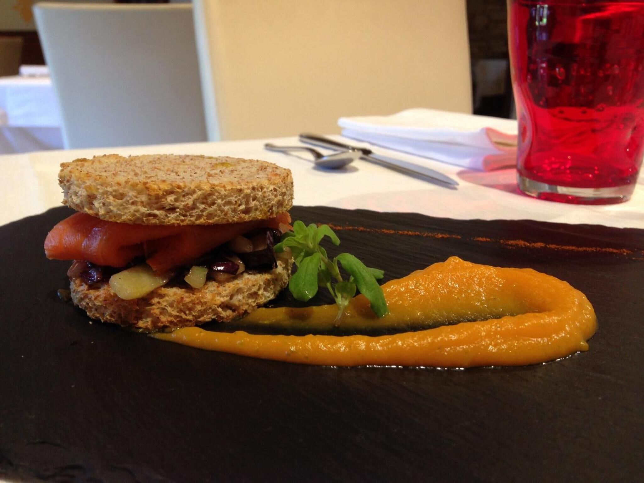 A sandwich with a side of sauce on a black plate.