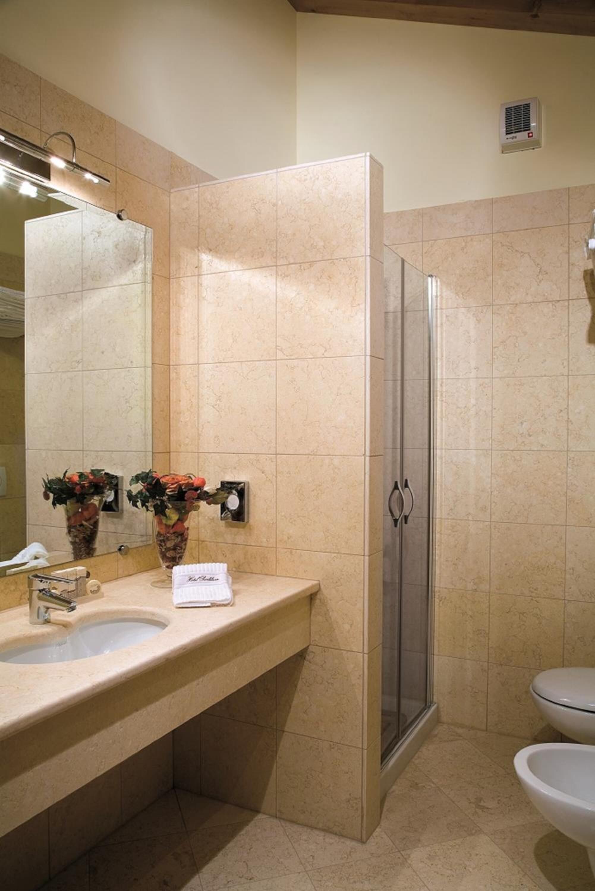 A bathroom with a sink, mirror, shower, and toilet.
