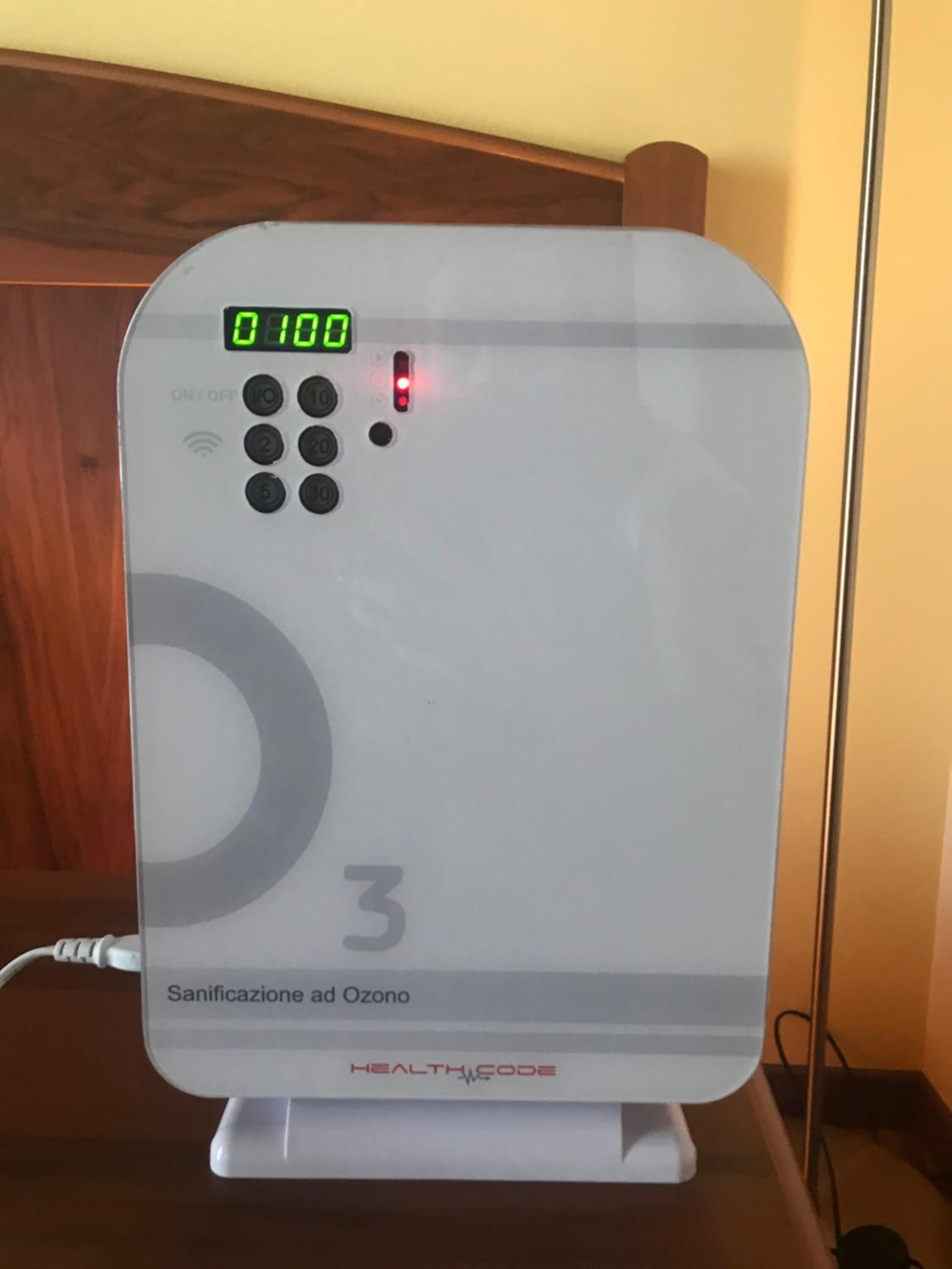 Un purificateur d’air blanc doté d’un écran numérique, d’un panneau de commande et de l’inscription « Sanificazione ad Ozone » sur la base.
