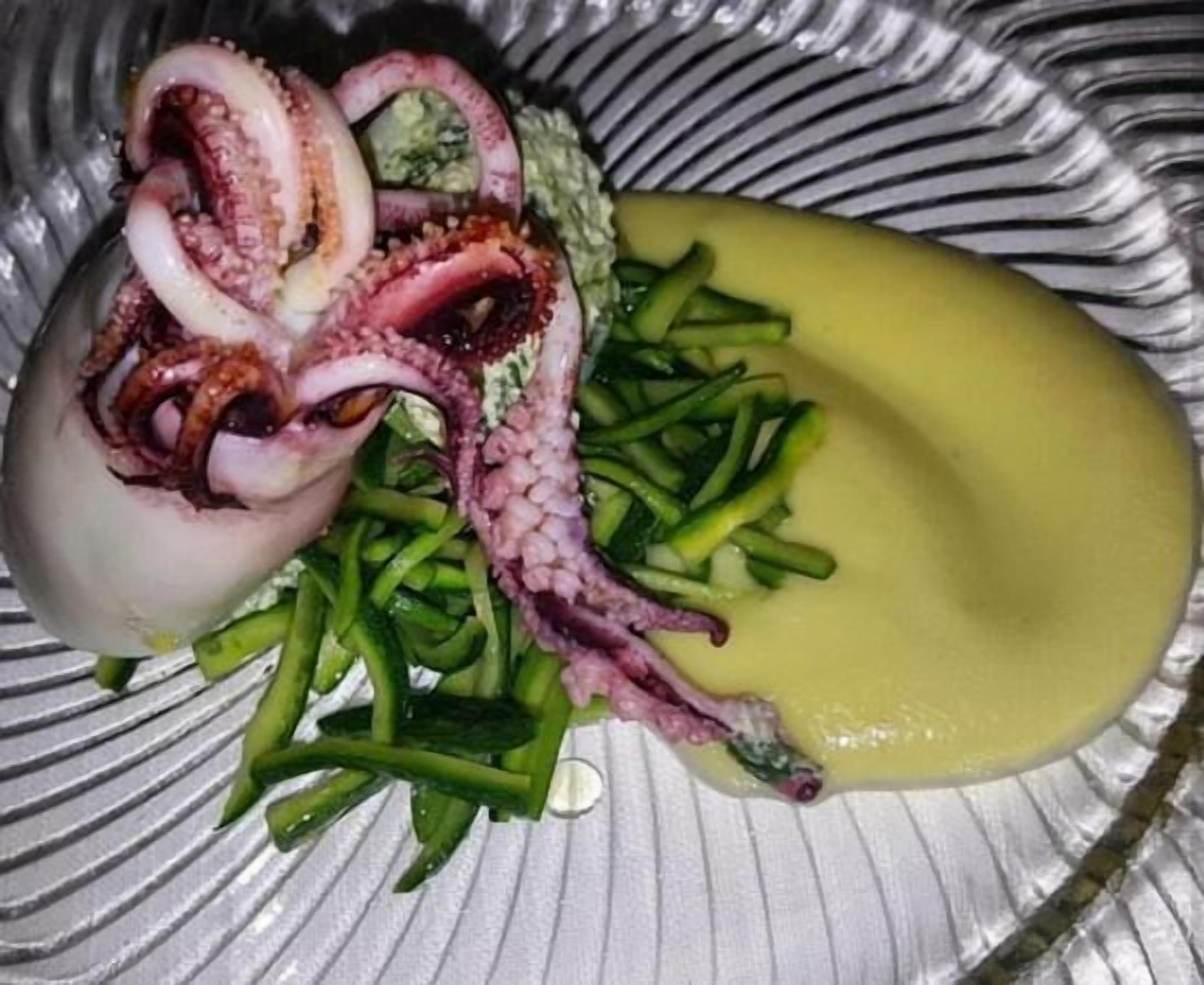 A plate with sliced octopus, green beans, and a yellow sauce.