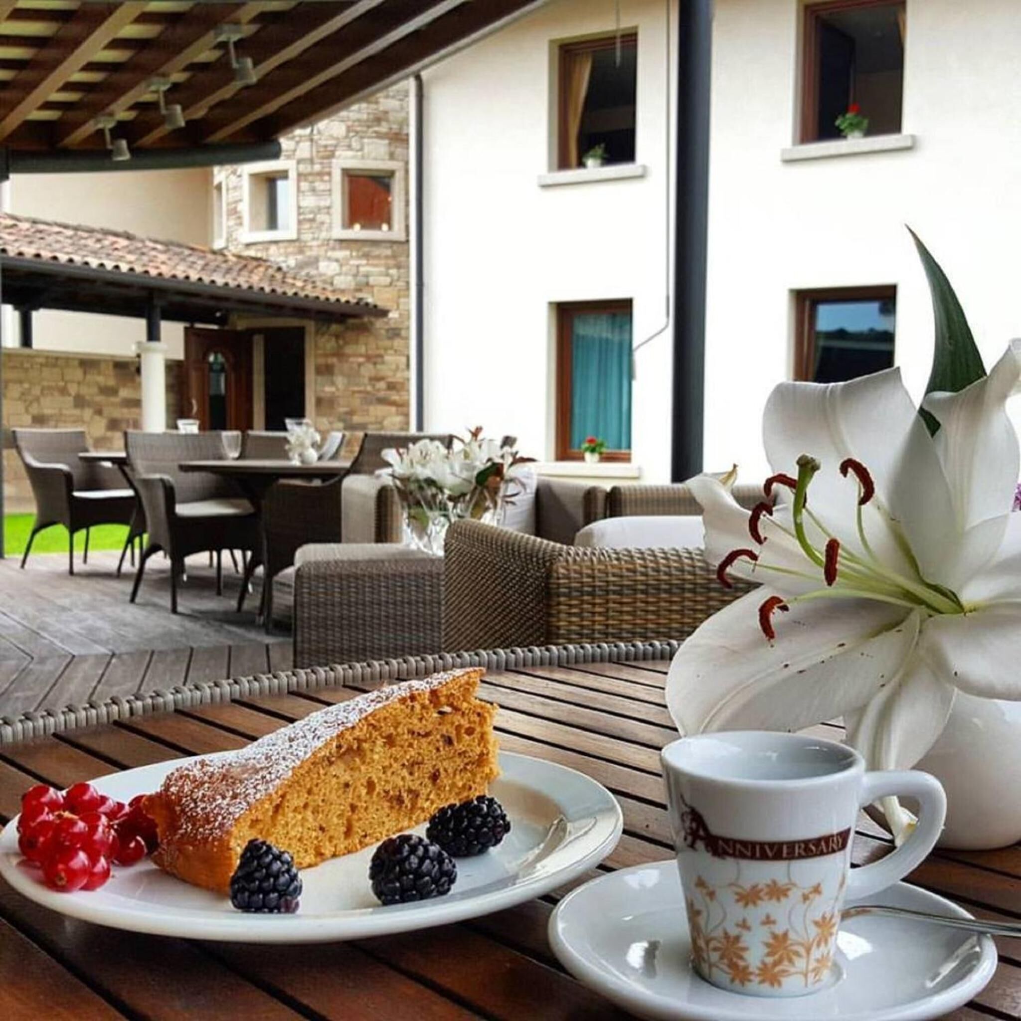 Una mesa de comedor con una porción de pastel, bayas y una taza de café.