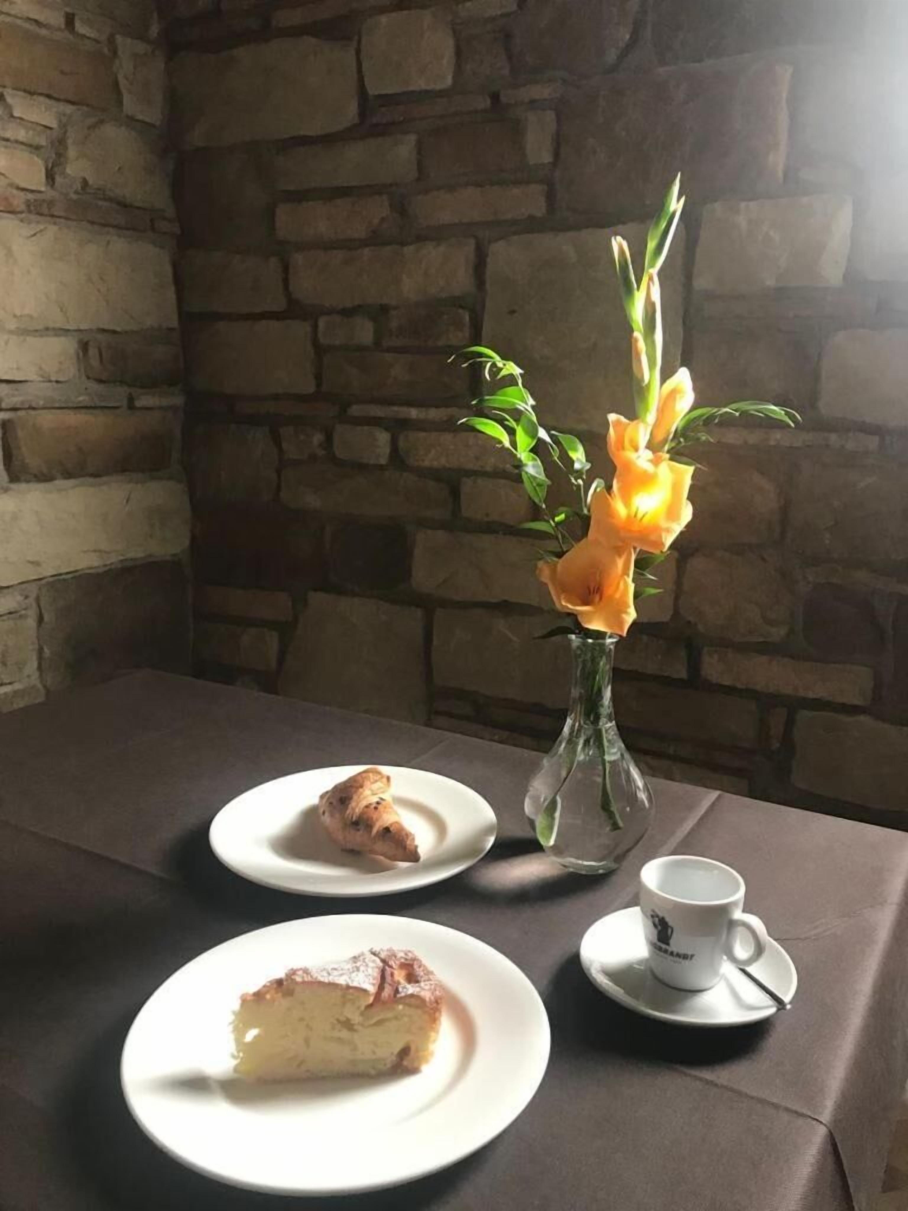 A table with a plate of food, a cup, and a vase with flowers.