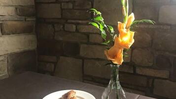 A table with a plate of food, a cup, and a vase with flowers.