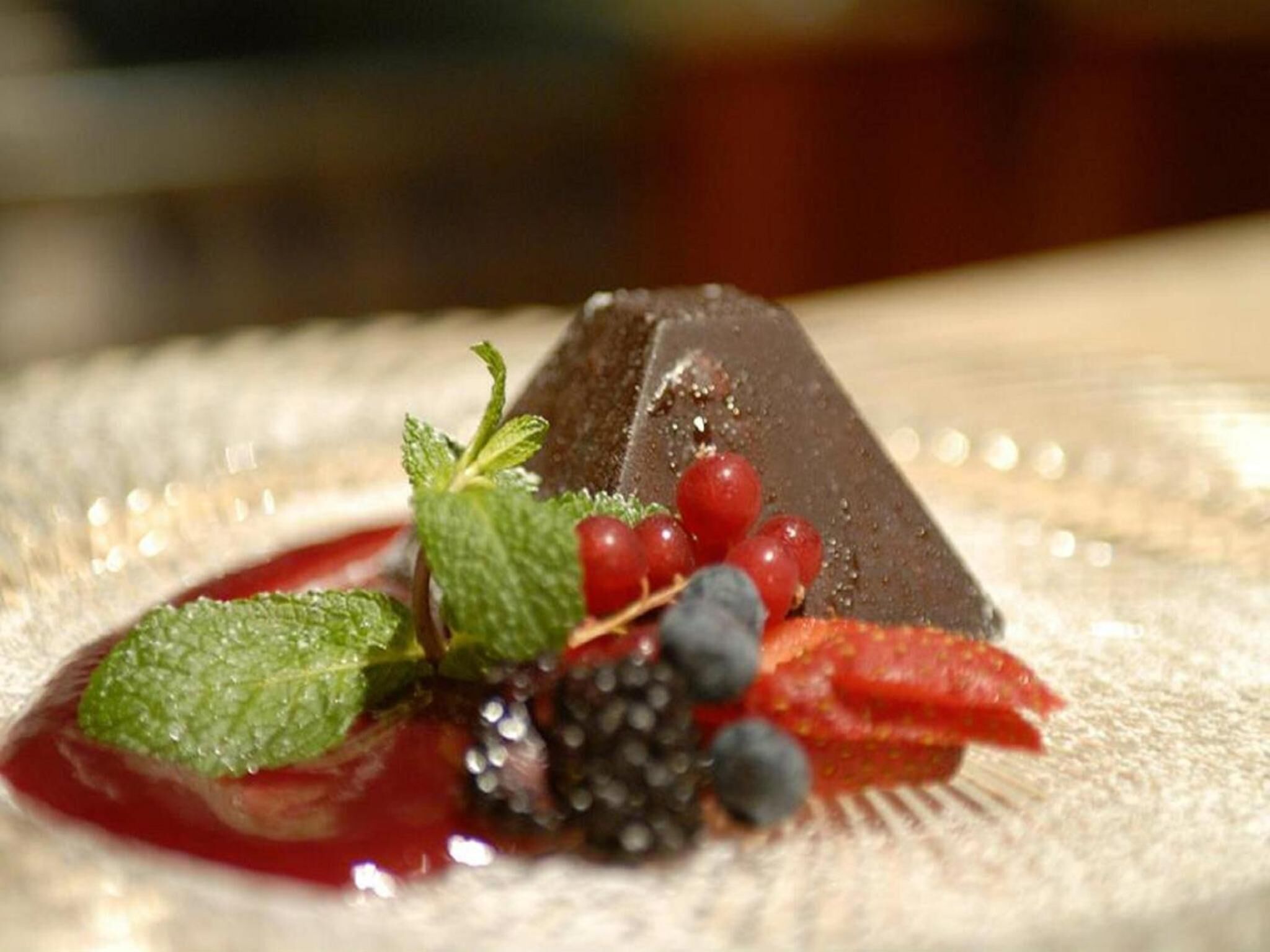 Un postre con bayas y hojas de menta en un plato.