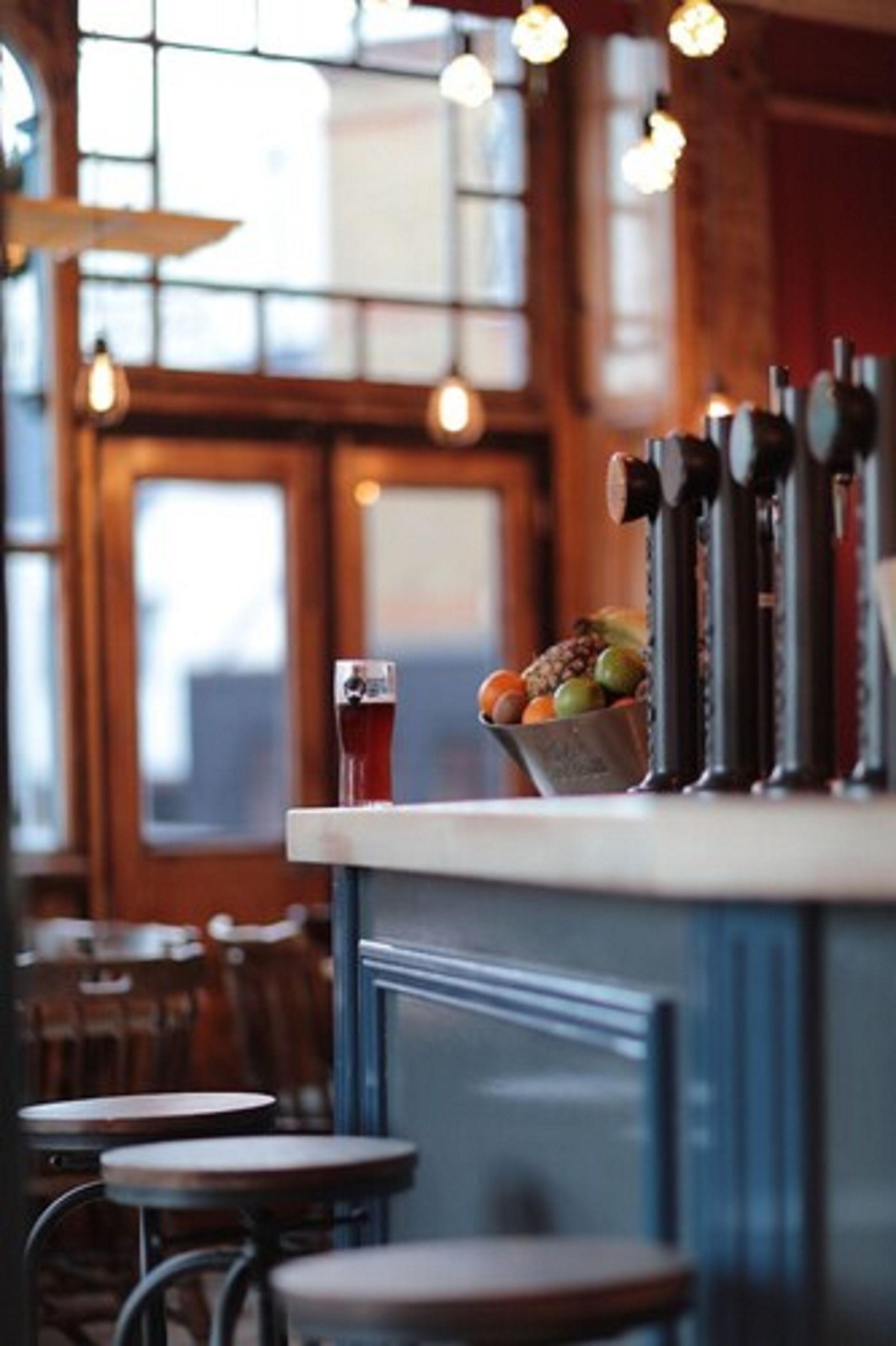 A bar area with a counter, a glass of red beverage, and a bowl of fruit.