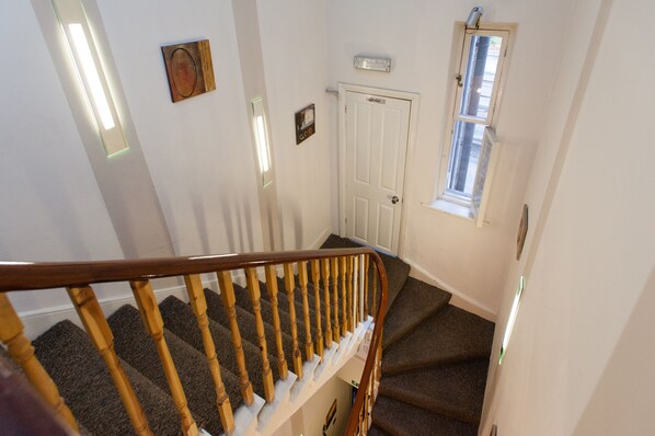 A staircase with wooden balusters and carpeted steps leading to a door with a window above it.