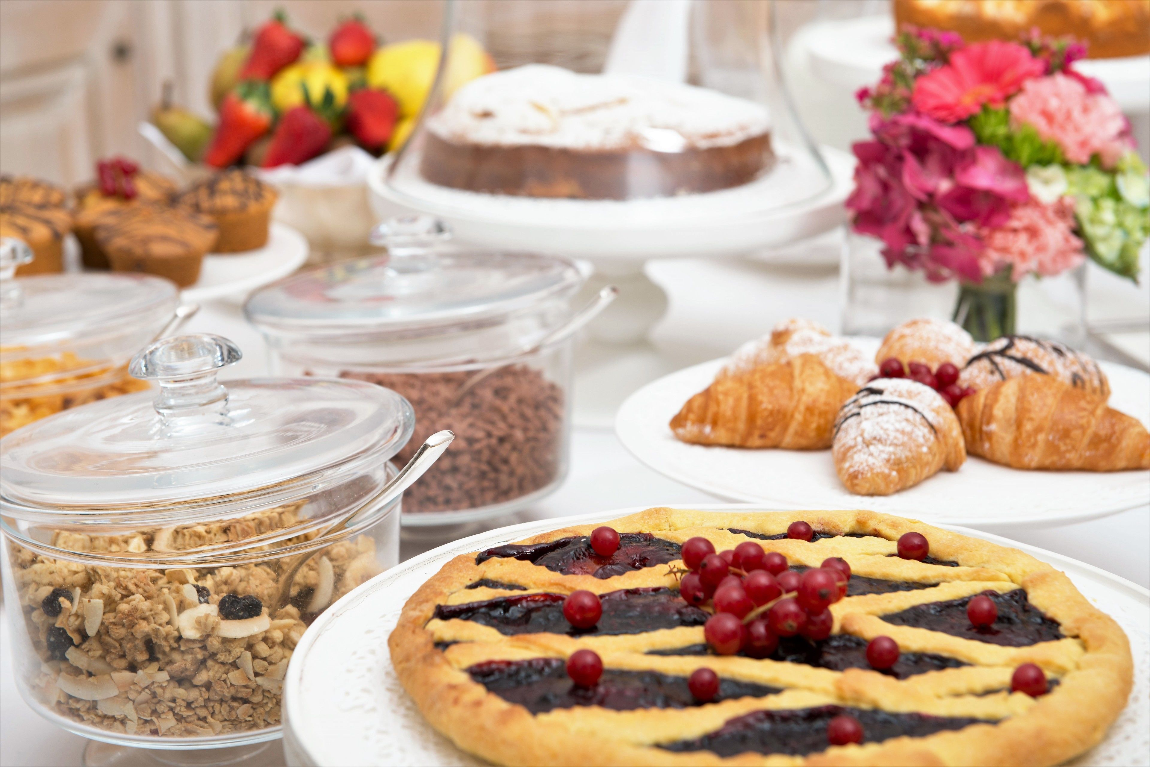 Variedad de productos horneados, incluyendo una tarta de cerezas, pasteles y un pastel sobre una mesa.