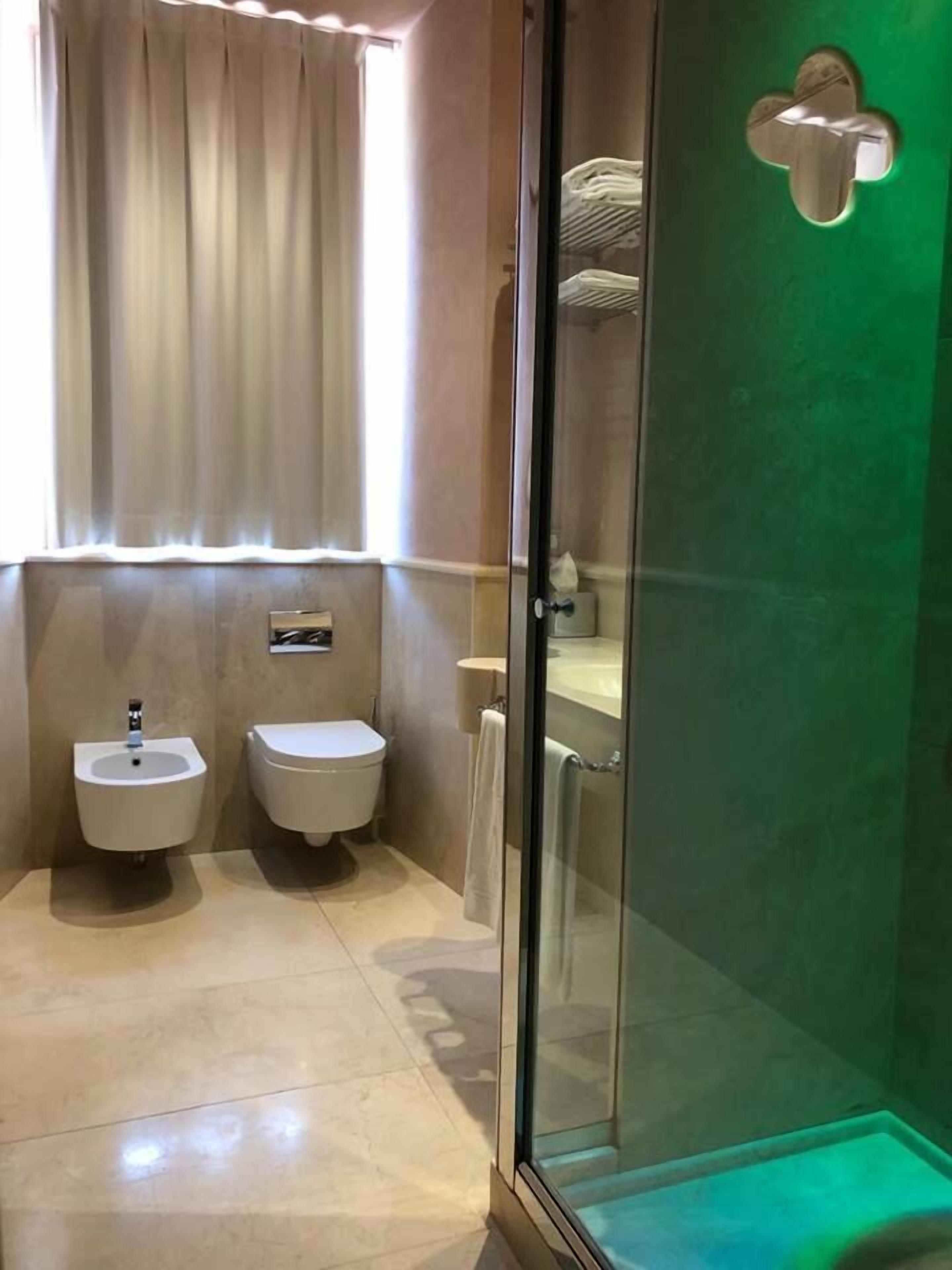 Un baño moderno con cabina de ducha de vidrio, dos lavamanos independientes y un inodoro.