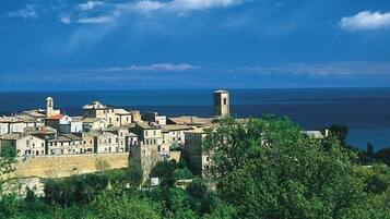 Un borgo costiero con edifici storici, una torre imponente e vista sul mare.