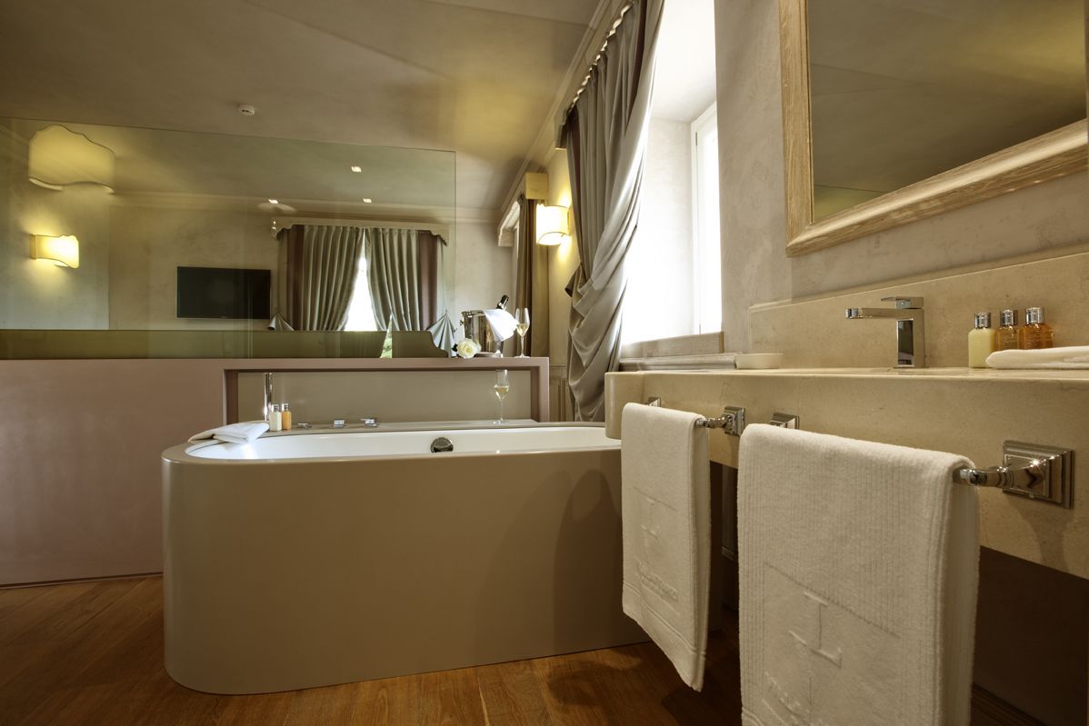 A modern bathroom with a freestanding bathtub, a large mirror, and a vanity with toiletries.