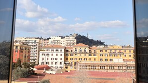 Blick auf eine Stadtlandschaft mit mehrstöckigen Gebäuden, einem klaren Himmel und einer entfernten Hügelkette.
