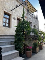 Un edificio de piedra con balcón, escalones y plantas en macetas.