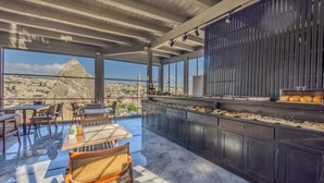 A rooftop dining area with a long counter, seating, and a view of a cityscape.