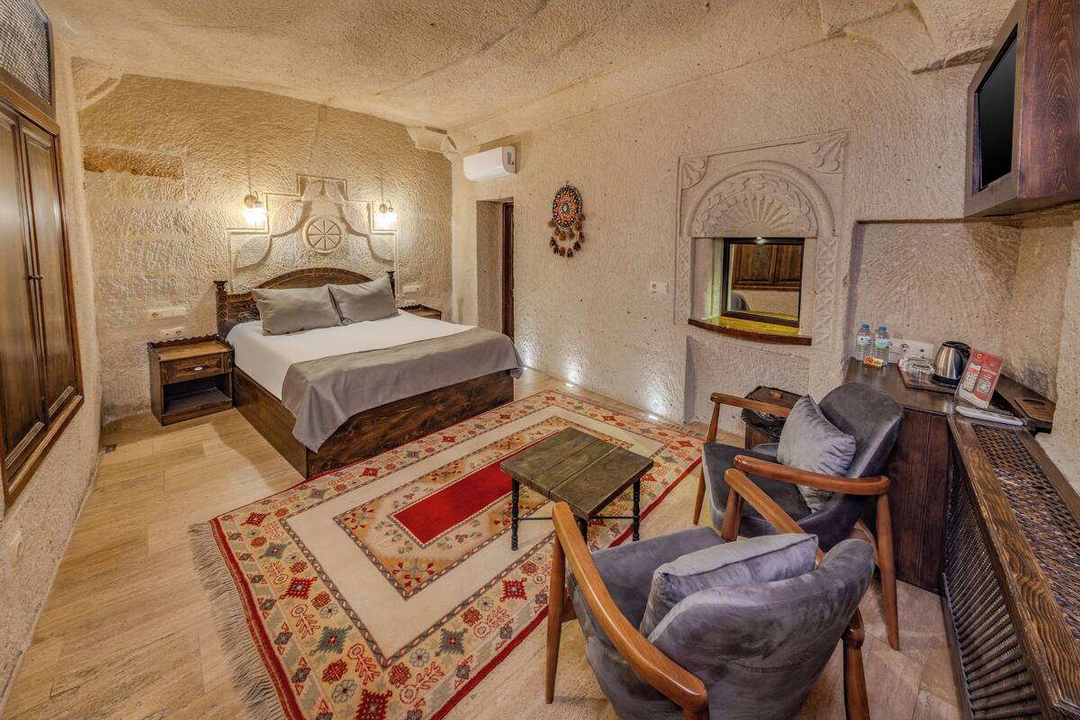 A bedroom with a bed, bedside table, chair, and a small table with a rug.