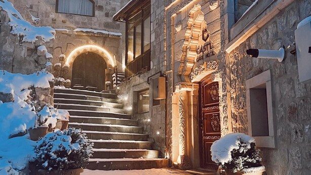 Un edificio de piedra con puerta de madera y escalones que conducen a él, rodeado de nieve.