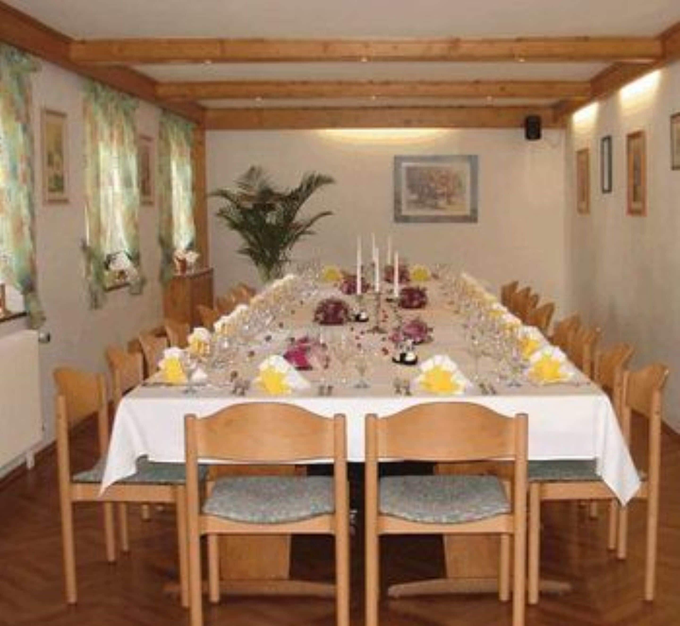 Una larga mesa de comedor preparada para una comida, rodeada de sillas.