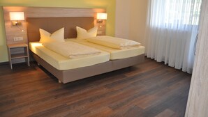 A double bed with two pillows, a nightstand, and a wall-mounted lamp. - Grüner Hof (Zell am Harmersbach)