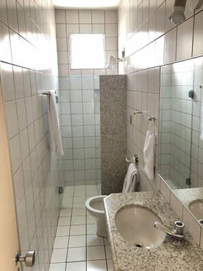 A small, tiled bathroom with a toilet, sink, and mirror. - Aldeota Praia Hotel (Fortaleza)
