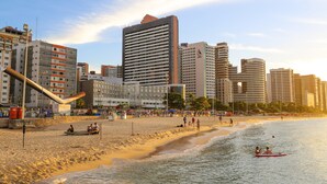 Una playa con un paisaje urbano al fondo, incluyendo edificios altos y una orilla arenosa.